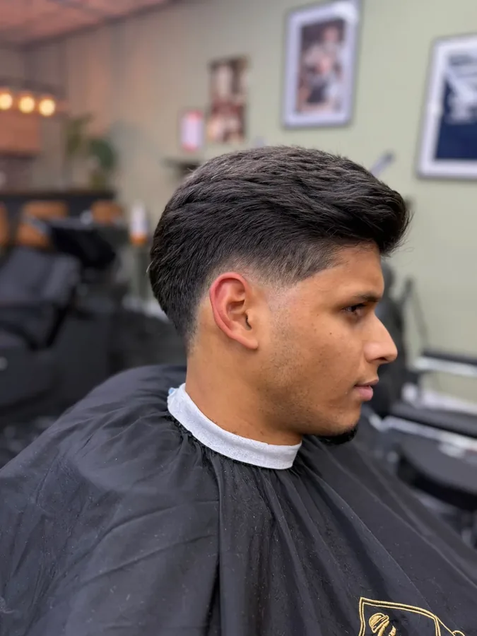 Donker haar met volume op de bovenkant en een taper fade