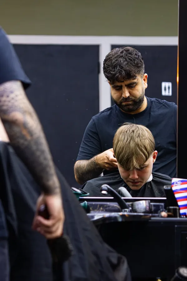 Barbier aan het werk bij een klant, gezien in de spiegel
