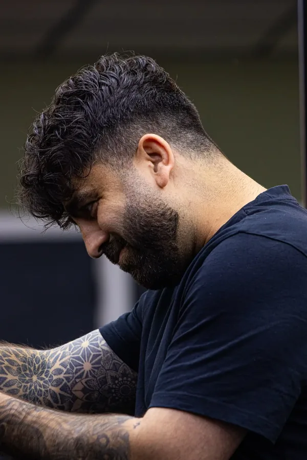 Barbier met krullend haar en baard aan het werk