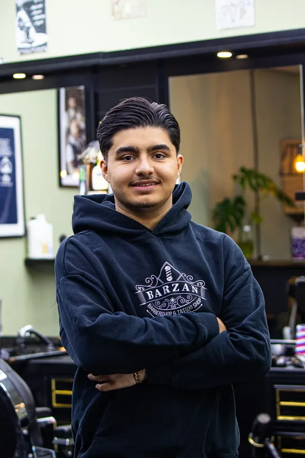 Medewerker van Barzan Barbers in een Barzan hoodie in de zaak